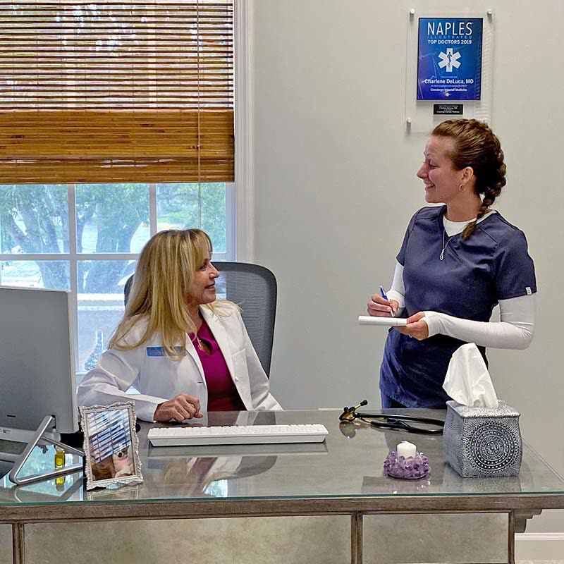 Dr. Charlene DeLuca at her desk with a member of her staff